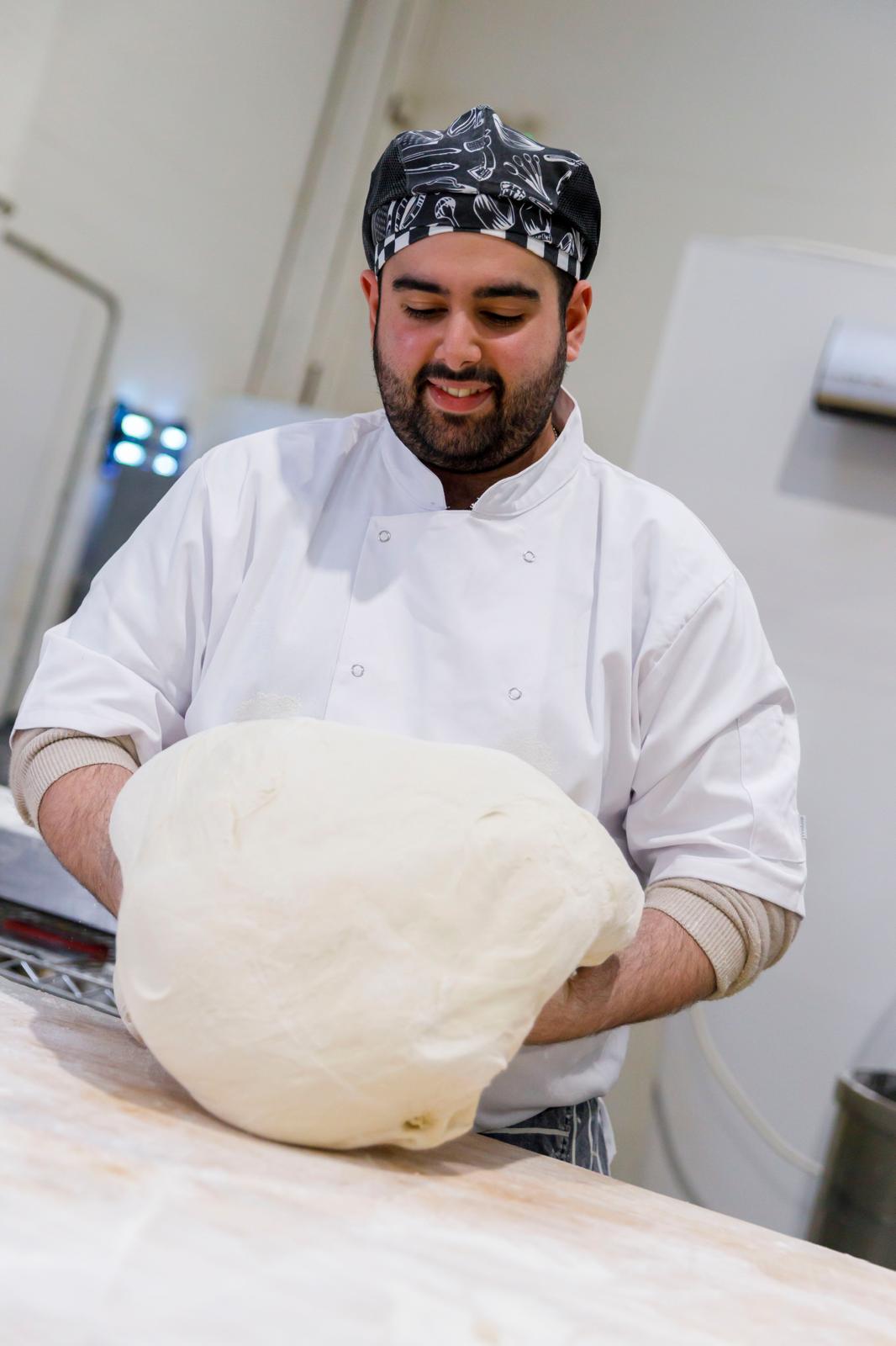 Baker shaping a large boule of dough